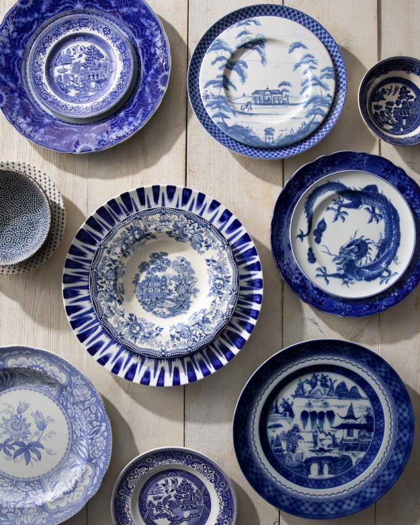 Various stacks of blue and white delftware plates on a white picnic table.