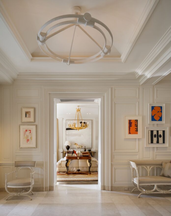 A modern and historic living room interior design by Féau Boiseries with white walls and paintings with pops of color.