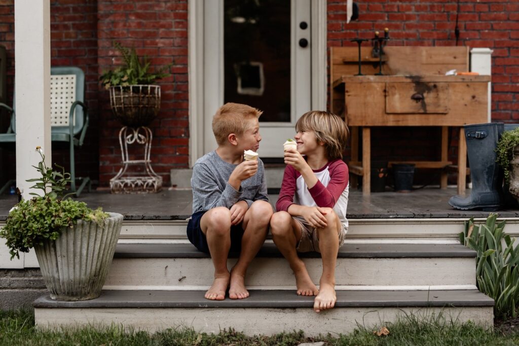Two small boys east pawpaw fruit ice cream on their porch.