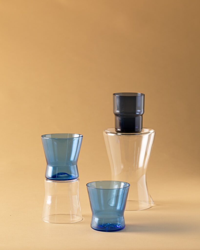 Two blue glasses and one black glass sit on a neutral brown background.