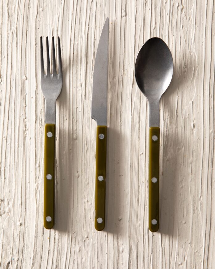 A fork, knife, and spoon in the same set sit on a white table.