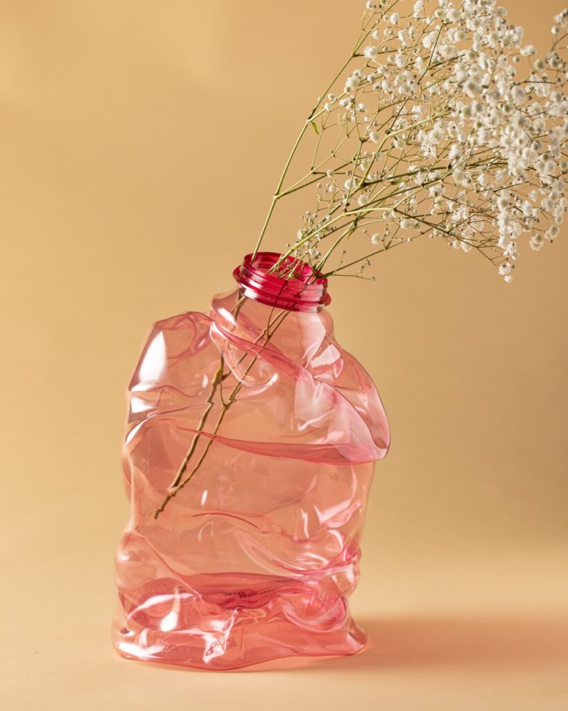 A surreal pink vase that looks like its melting with baby's breath in it.
