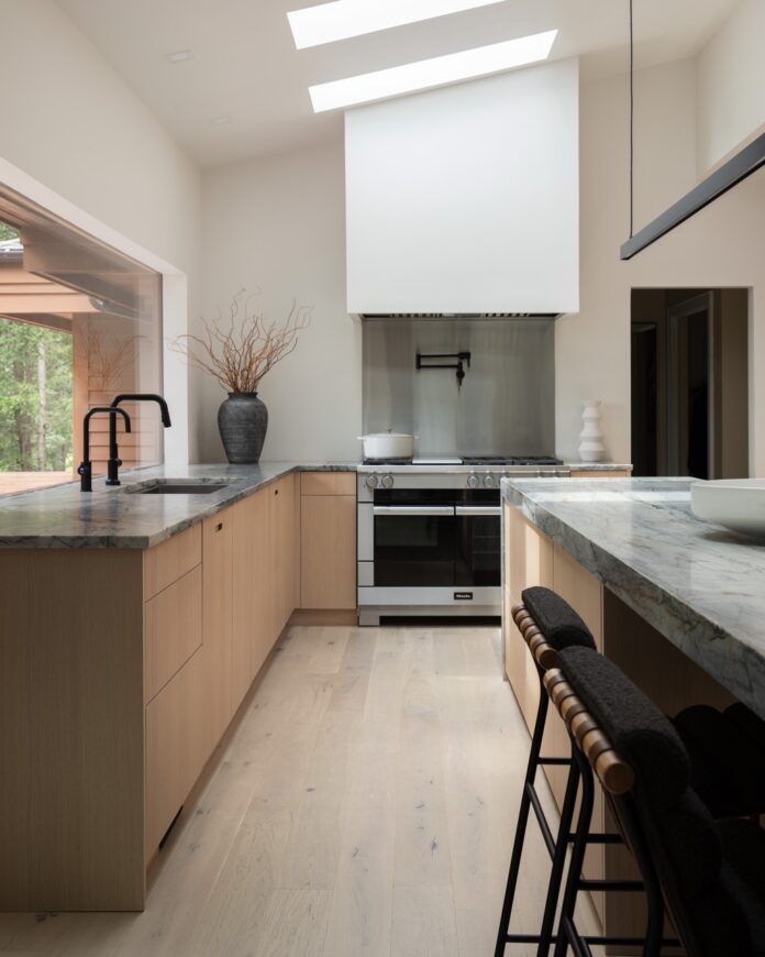 Tolga Sevdik from Richard DeShantz Restaurant Group's modern kitchen with wood cabinets, dark countertops, and skylights.
