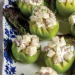 Cut open apples hold a gilded age Waldorf Salad on a blue and white plate.