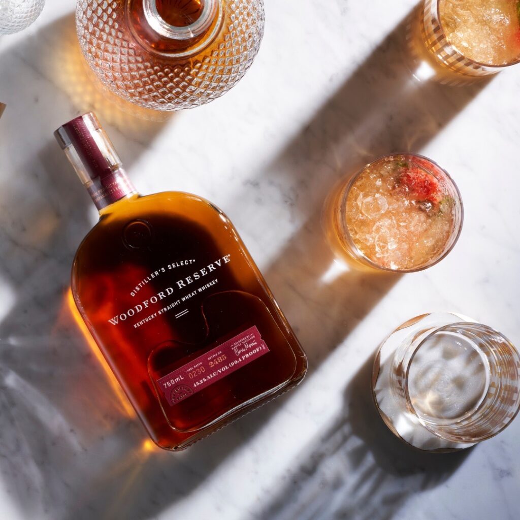 A bottle of bourbon whiskey for father's day beside glasses of whiskey cocktails.