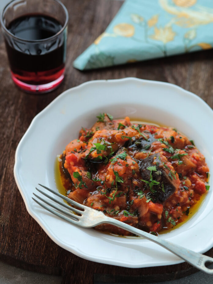 A white dish of a culinary food tour in Greece with a red stew.