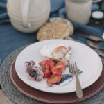 A white plate holds baby octopus, scallops, and sardines as a part of a seafood picnic.