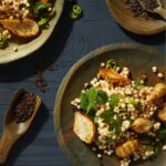 Roasted Sunchokes and Herbed Couscous with wooden plates and a wooden spoon on dark background