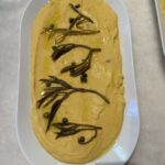 An aerial shot of a Fava Spread, yellow in color, on a white oval dish