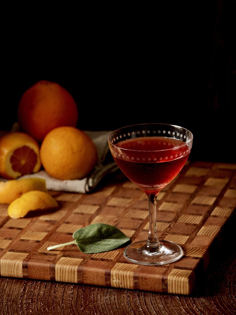 Oaxacan Nights Negroni on checkered board with fruit background