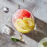 A mocktail with watermelon ad lemon garnish.
