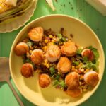 Seared Scallops with Warm Corn & Chorizo Salsa on a yellow dish with green background.