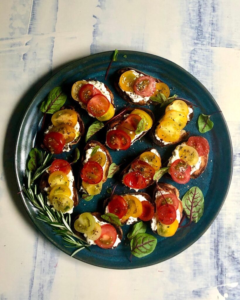 Tomato-Ricotta-Burschetta on dark plate with light background