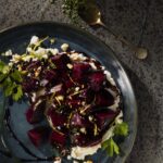 An aerial shot of a dark blue plate holding a serving of roasted beets