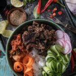 A beef bulgogi bowl with rice, cucumbers, radishes, carrots, and beef.