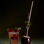 A Bourbon Apple Smash cocktail in a glass, next to a caramel-dipped apple.