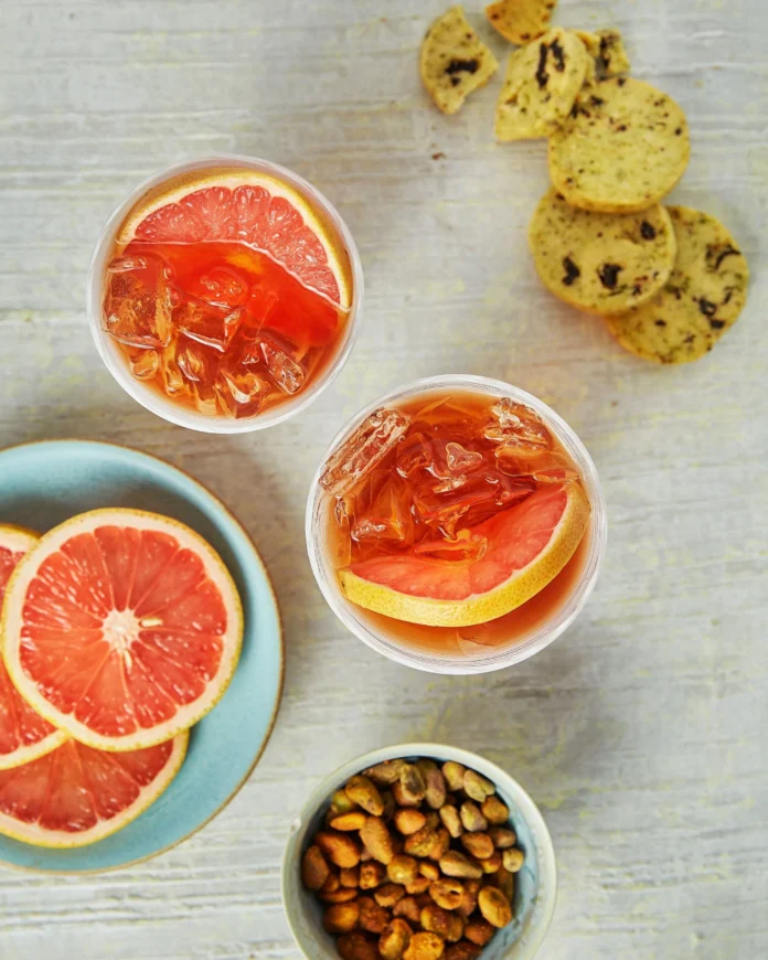 An above shot of two glasses filled with an orange liquid, Bourbon Paloma.