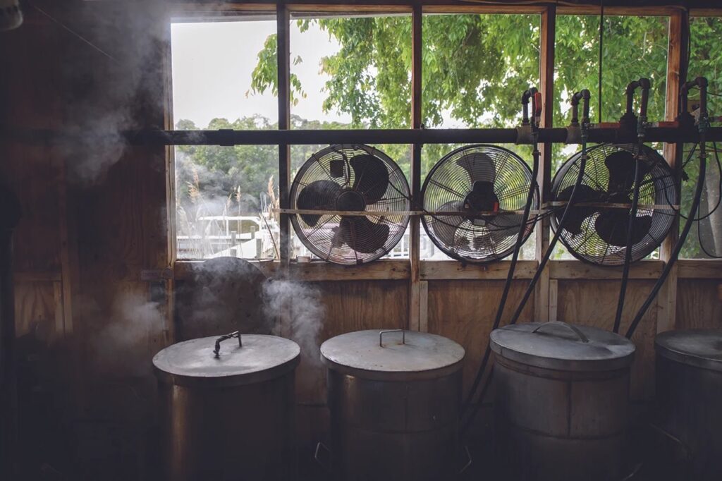 Four steaming pots sit below a window of fans.