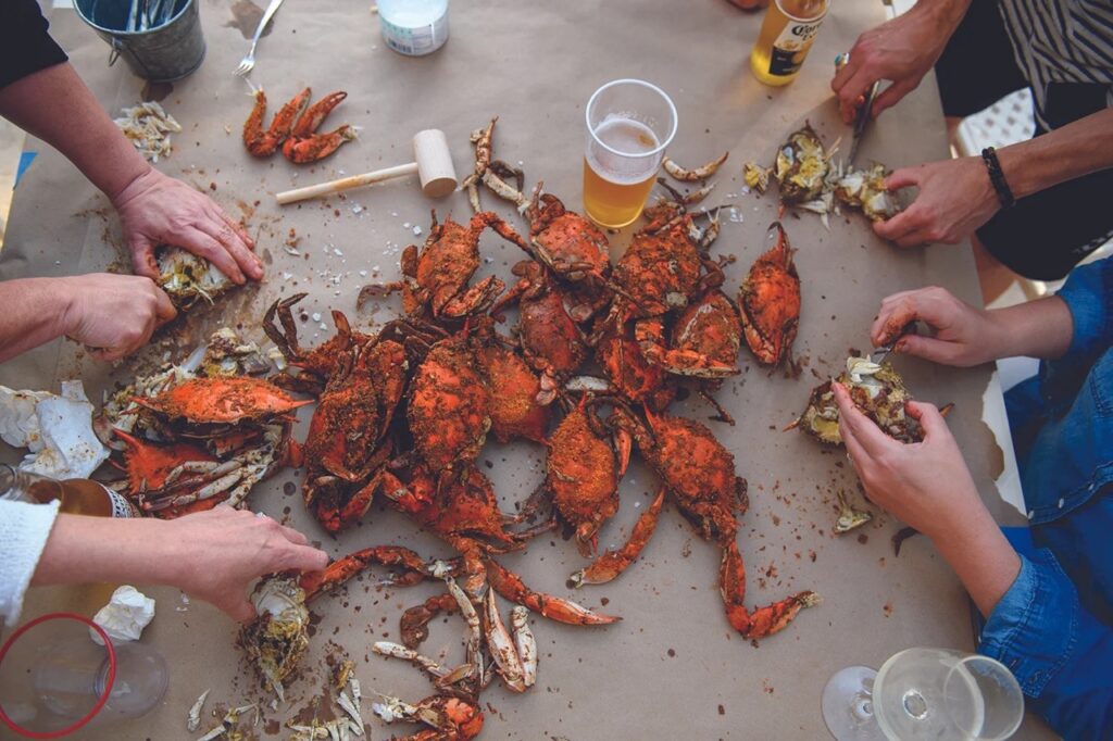 People crack open crabs on a brown paper table.
