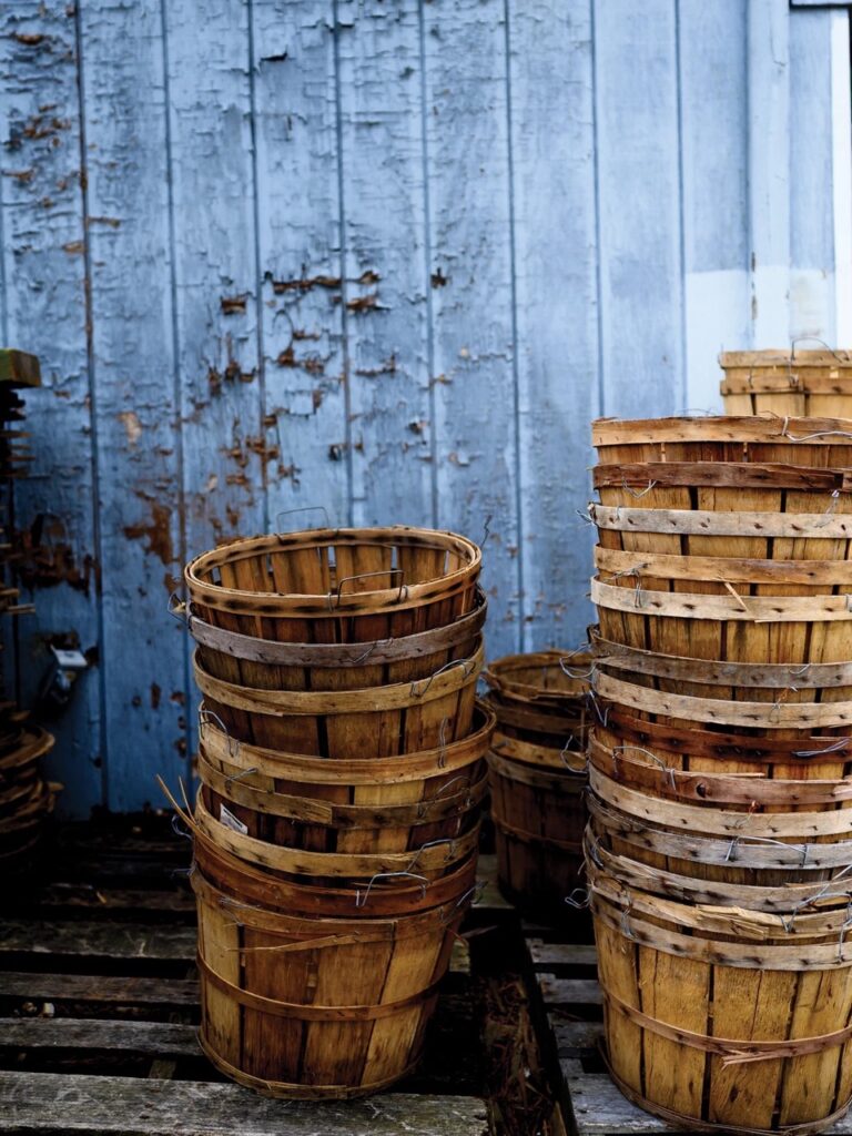 Three stacks of wooden buckets in front of a shed.