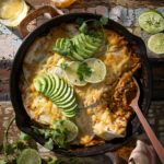 Creamy enchilada with limes and garnishes in a skillet