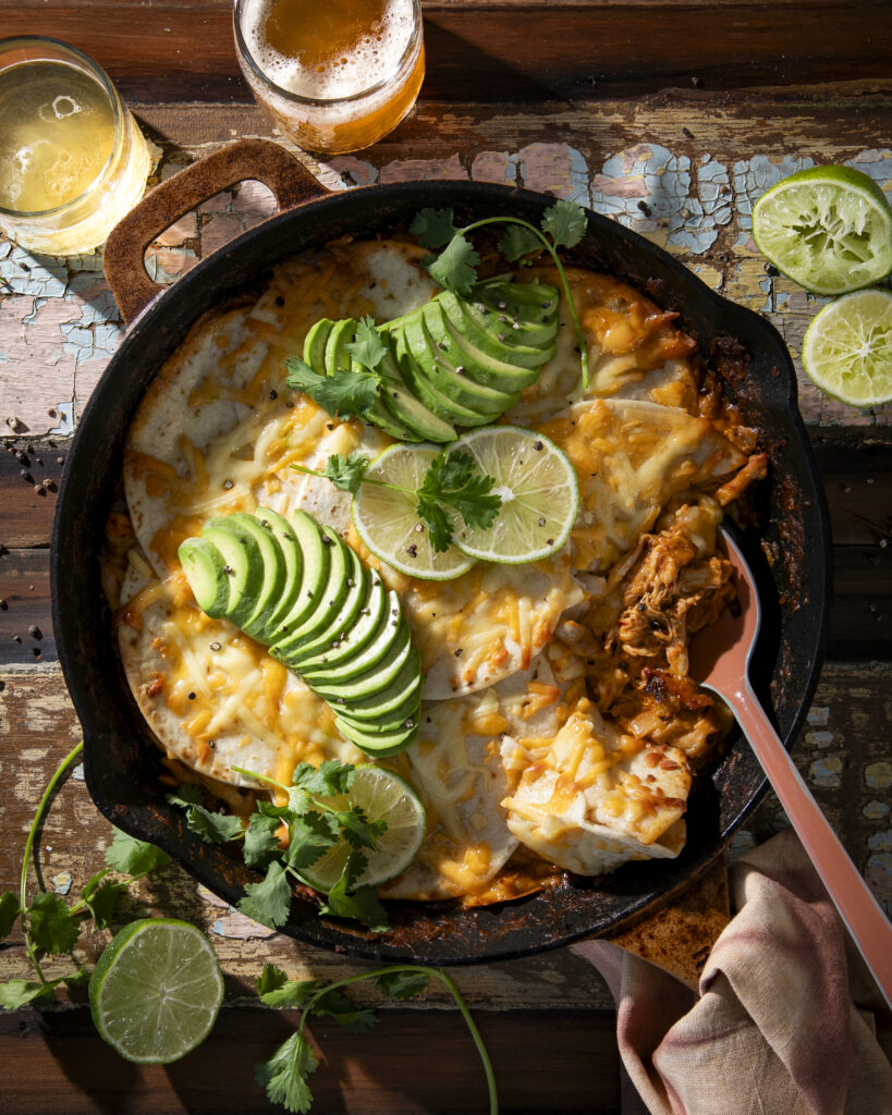 Creamy enchilada with limes and garnishes in a skillet