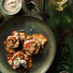 A green plate with Martha Stewart-Inspired Stacked Eggplant Parmesan individually on a plate with a beschamel sauce off to the side.