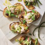 A variety of Pesto-Burrata Crostinis with spears of asparagus beside them.