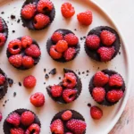 An above shot of eight Raspberry Truffle Tartlets sitting on a white round tray