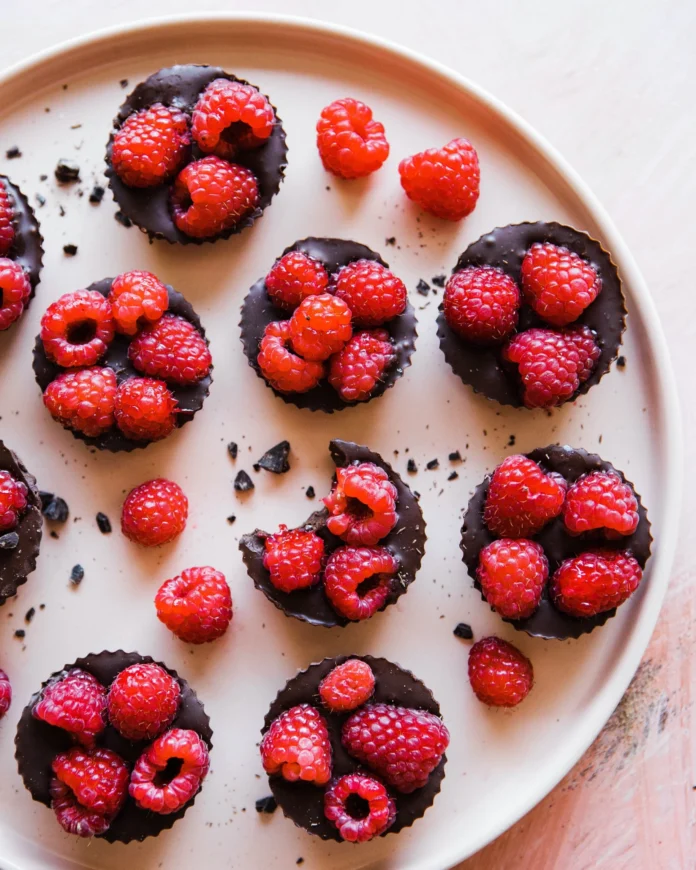 An above shot of eight Raspberry Truffle Tartlets sitting on a white round tray