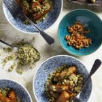 Blue-and-white patterned bowls filled with roasted eggplant, topped with a green crumble, with a separate bowl of dried anchovies.