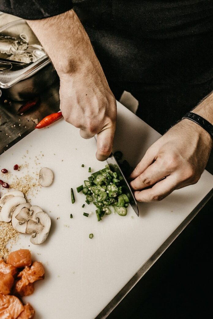 A chef chops up ingredients on a cutting board in the kitche.
