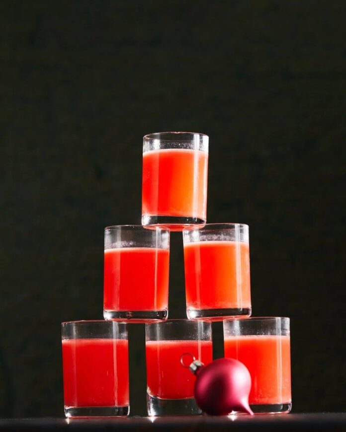 A tall pyramid of small glasses filled with a vibrant red-orange 