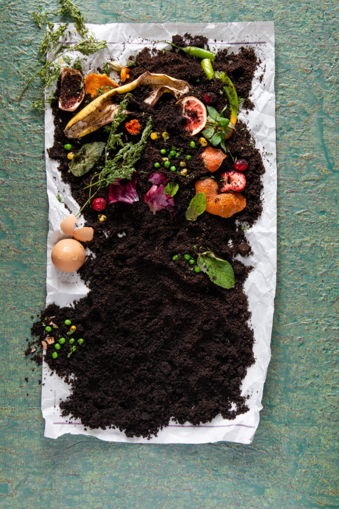 A pile of compost with soil and scraps on a white paper towel.