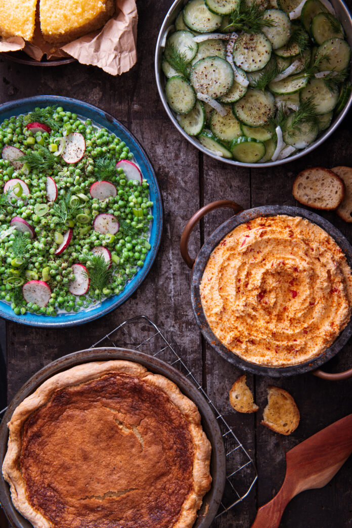 Southern Cookbook Recipes from Ronni Lundy Four southern recipes sit on a picnic table from salad to dessert.