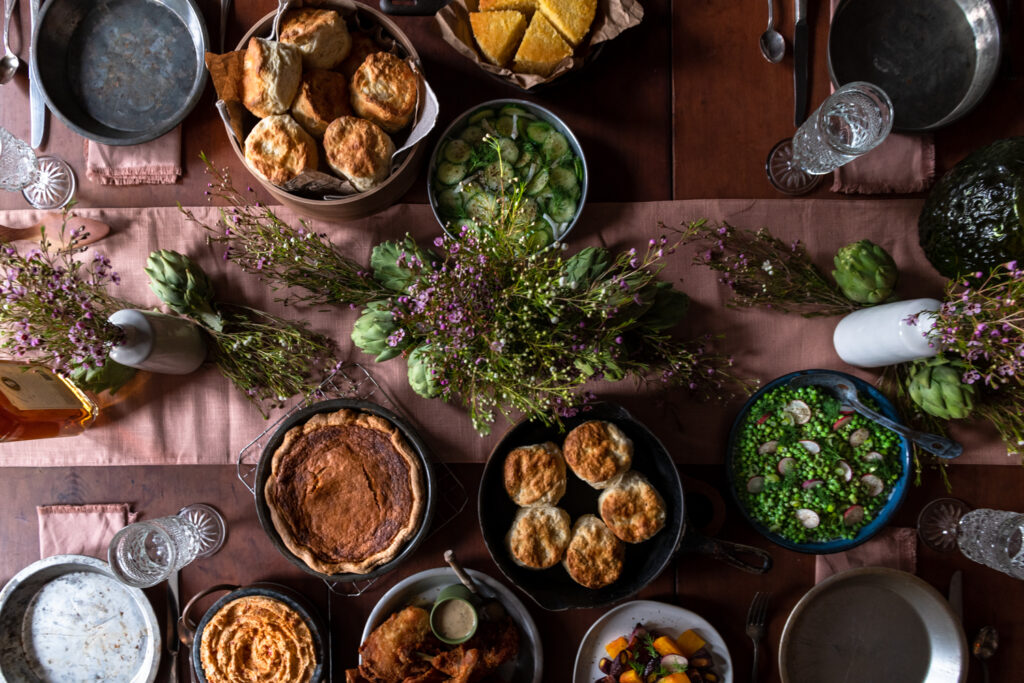 A picnic table full of classic southern recipes like pie, soup, rolls, etc.