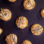 The cranberry coconut macaroons drizzled with white and dark chocolate on a dark brown background.