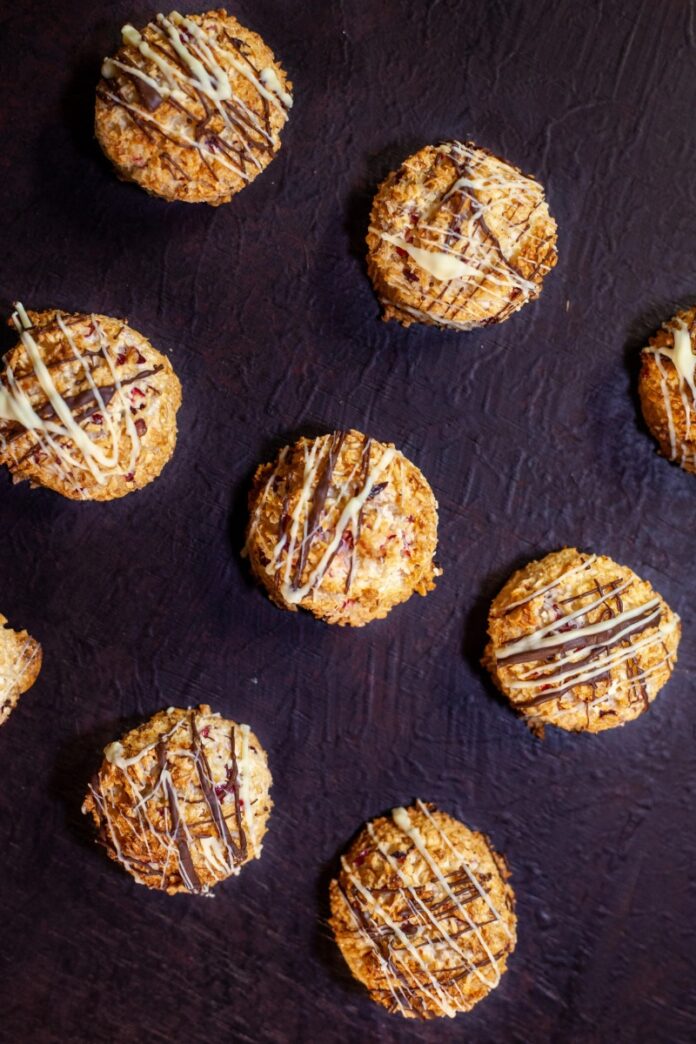 The cranberry coconut macaroons drizzled with white and dark chocolate on a dark brown background.