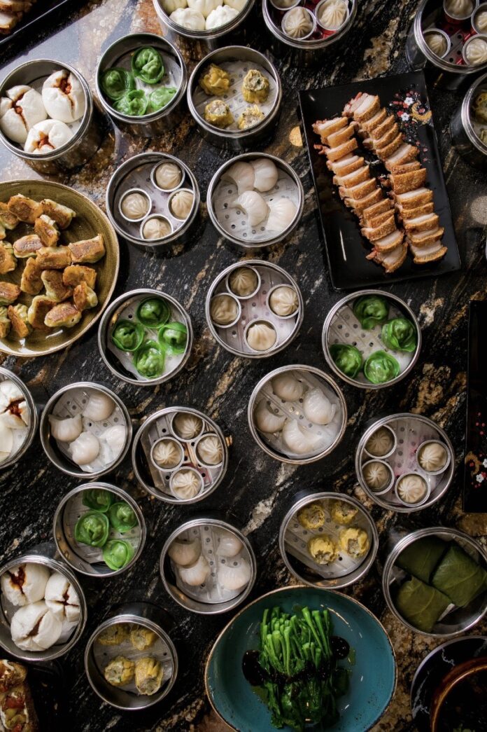Taro Dumplings A variety of dumplings placed in round silver pans fill up a large dining table.