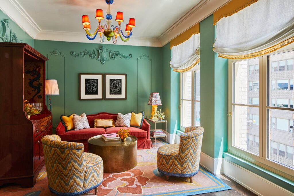 A red couch and pattern chairs in a mint green walled space.