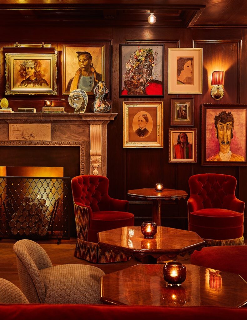 A red chair lounge area with art on the walls above the fireplace.