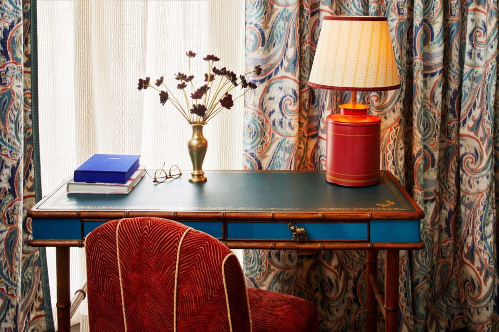 A blue vintage desk with a red velvet chair.