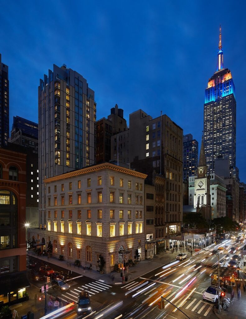 The nighttime outside view of the Fifth Avenue Hotel skyline.