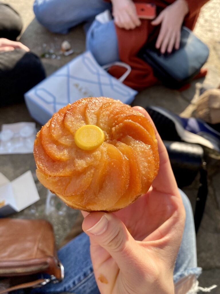 A person holds a French pastry that looks similar to a croissant bun.