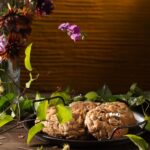A plate full of candy cookies with googly eyes candies on them amongst flowers and vines.