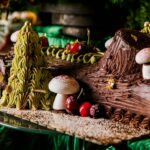 A close up shot of a heavily decorated black forest cherry bouche de noel (yule log).