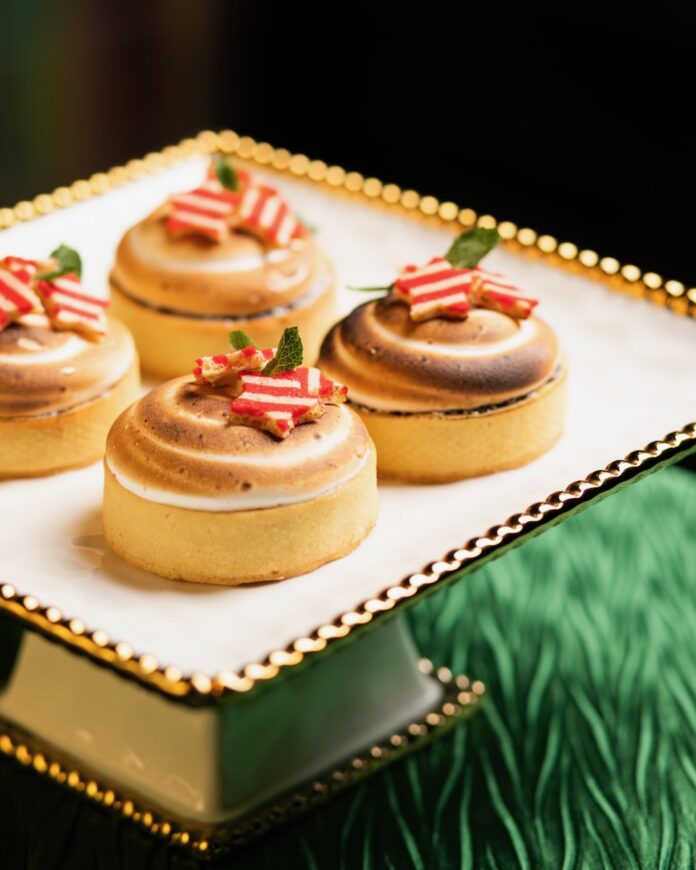 Four smaller circle tarts with peppermint candies on top, all on a green table top.