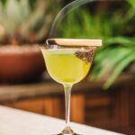 Margarita Verde with smoking wood as garnish greenery in the background