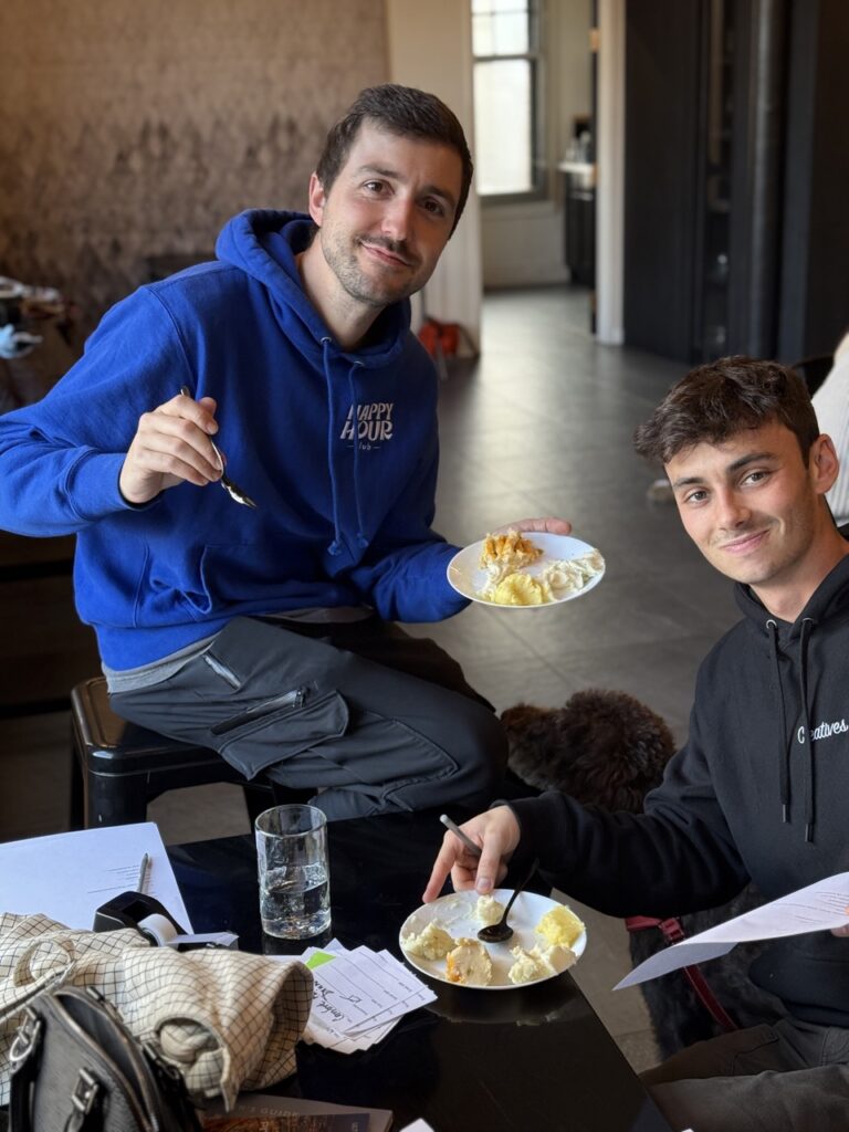 Two men eat mashed potatoes at a table.