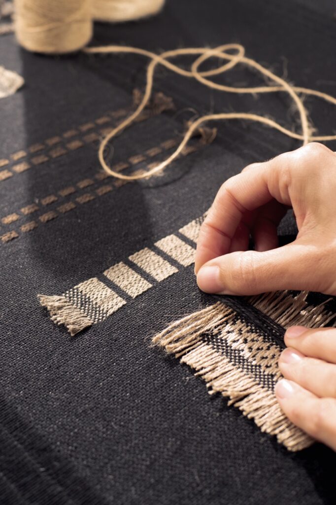 A person embroidering a rug.